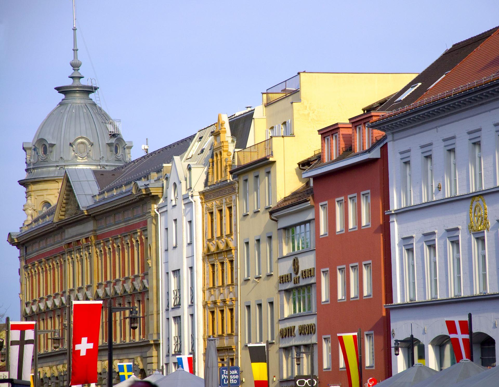 Bunte historische Gebäude mit internationalen Fahnen in einer Stadt am Bodensee.