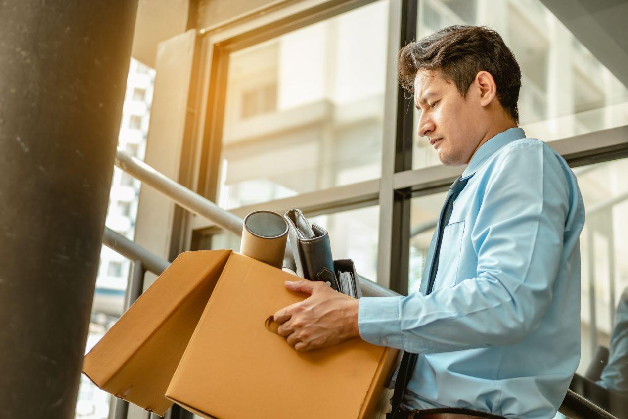 Gekündigter Arbeitnehmer verlässt mit Karton das Büro – mögliche Ausgangssituation für eine Kündigungsschutzklage.