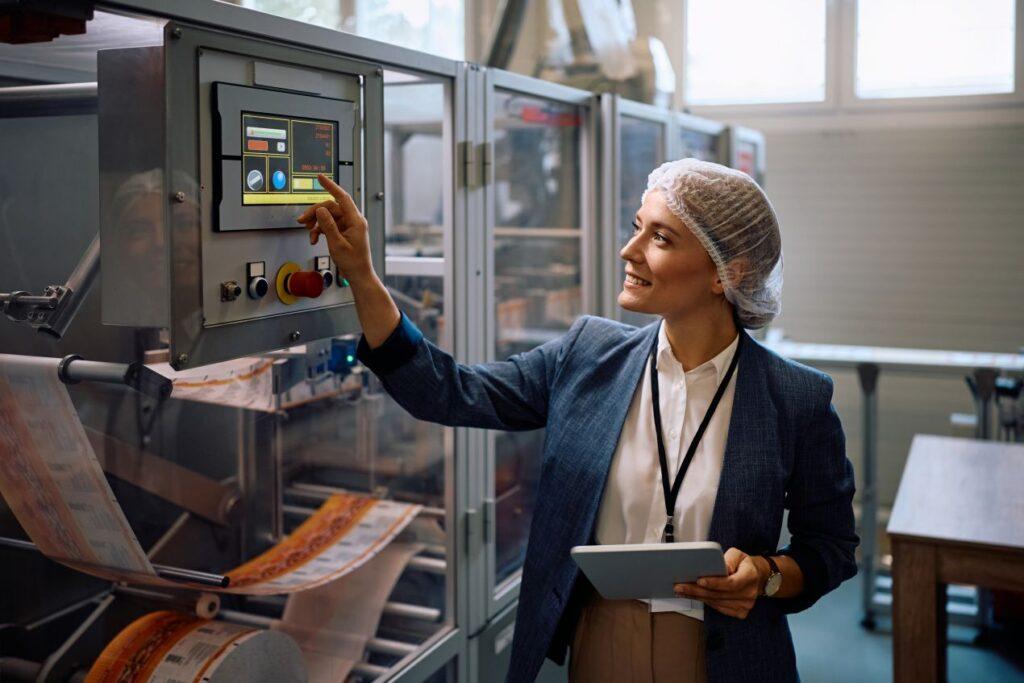 Fachkraft bedient digitales Bedienfeld in moderner Produktionshalle zur Blechbearbeitung